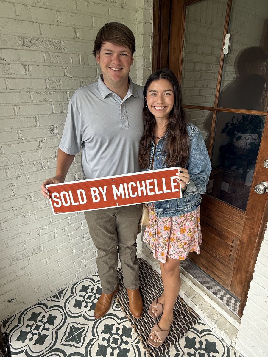 Michelle’s clients holding a Sold by Michelle sign on a front porch