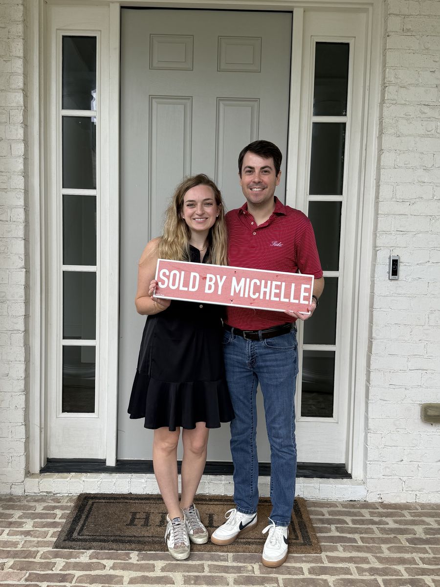 Michelle’s clients holding a Sold by Michelle sign at a front door