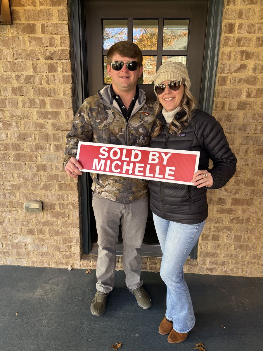 Michelle’s clients holding a Sold by Michelle sign outside their home