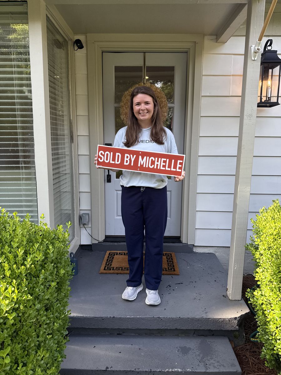One of Michelle’s clients holding a Sold by Michelle sign on her front steps