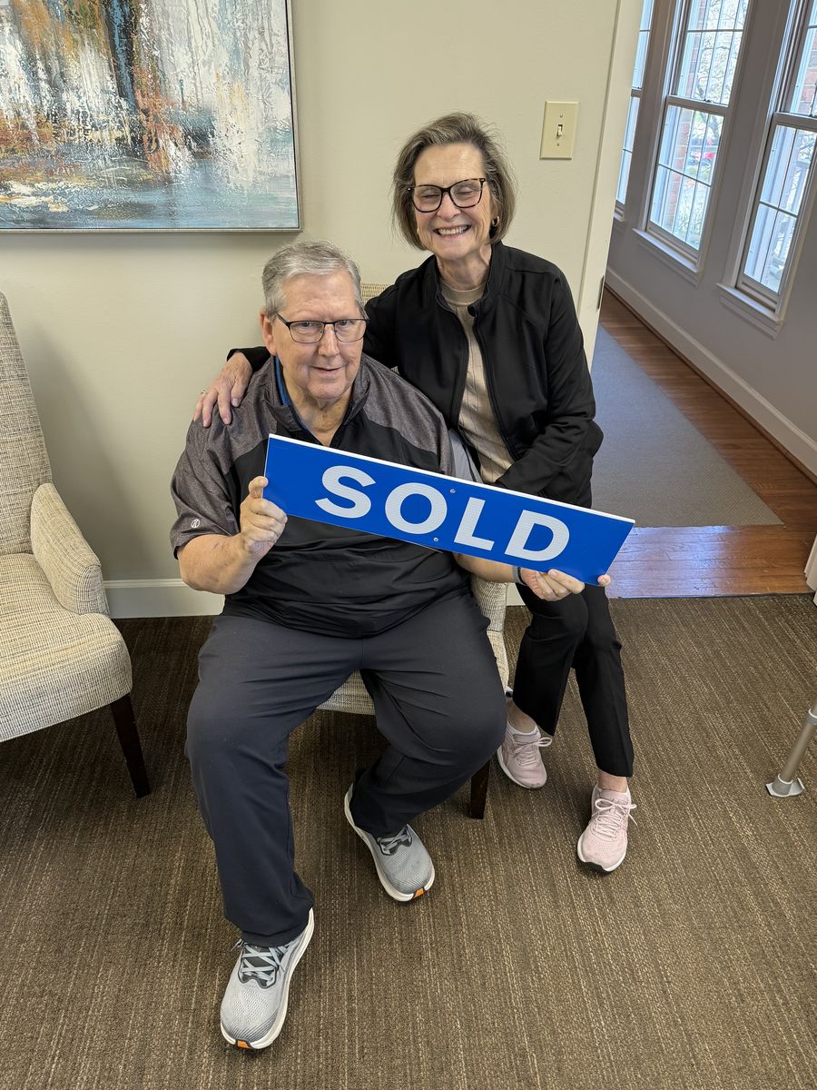 Michelle’s clients holding a Sold sign inside a home