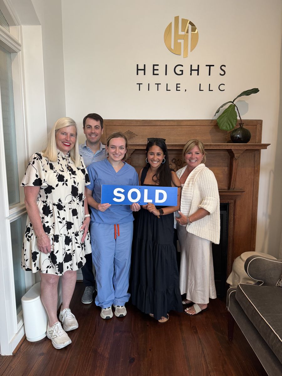 Michelle’s clients holding a Sold sign at the closing office